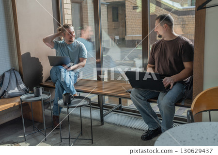 Two laughing It Software engineers working on project and programming in coffee shop. Successful start up project concept. 130629437