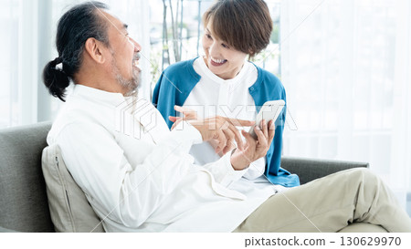 Senior couple looking at smartphone on sofa 130629970