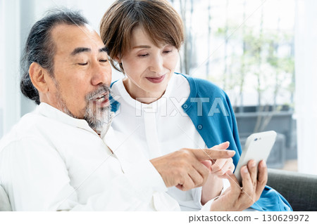 坐在沙發上看智慧型手機的老年夫婦 130629972