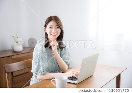 穿著休閒服的年輕漂亮女人在家裡的房間裡用筆記型電腦看著相機 穿著休閒服的年輕漂亮女人在家裡的房間裡用筆記型電腦看著相機 130631770