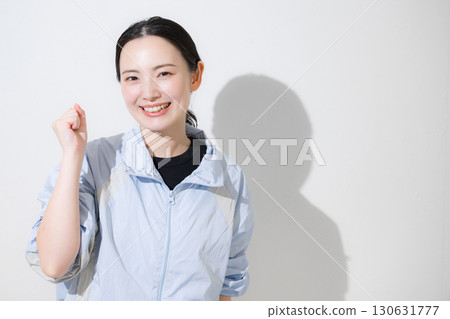 一位身穿運動服的女士揮舞著拳頭歡呼，微笑著看著鏡頭。我會努力控制飲食和運動的！ 130631777