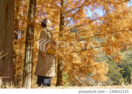 Middle-aged woman walking among autumn leaves 130632135