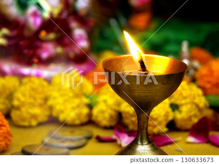 Burning Brass Diya with Flowers in Background 130633673