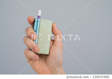 Woman holding electronic cigarette on white background. Tobacco heating systems. 130635960