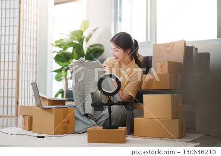 Online Shopping. Woman showcasing a sweater while sitting in a cozy home environment. 130636210