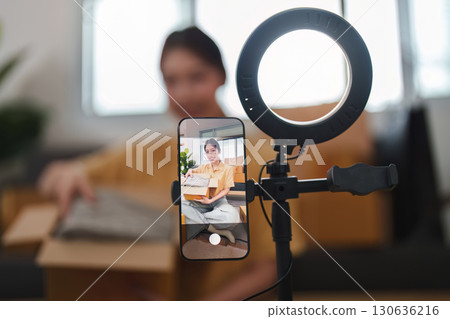 Online Shopping. Woman smiling while holding a sweater in front of a smartphone. Online Shopping. Woman smiling while holding a sweater in front of a smartphone. 130636216