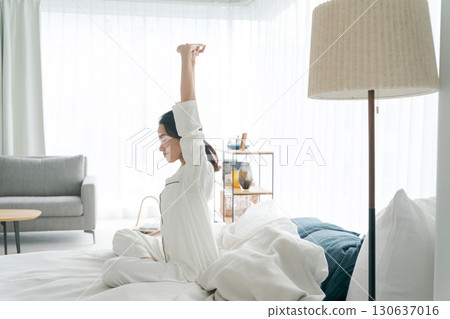 A woman in pajamas getting up and stretching A woman in pajamas getting up and stretching 130637016
