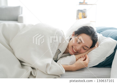 A woman in pajamas sleeping on a futon 130637101