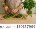 A person chopping fresh herbs on a wooden board with a basil bouquet in a glass nearby. Generated AI. 130637964