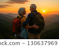 An elderly couple with backpacks embraces while watching the sunset over scenic mountain ranges. Generated AI. 130637969
