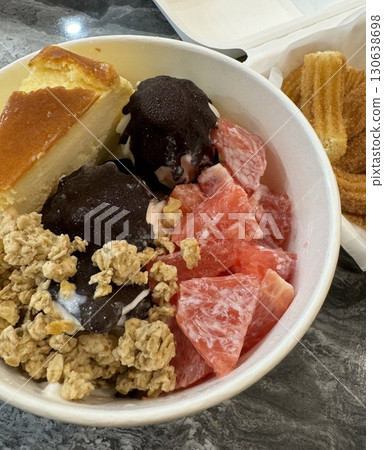 Swirled yogurt ice cream dessert served in a cup, smooth creamy texture with glossy surface, topped with fresh fruit pieces, highlighting its refreshing and inviting appearance in detail Swirled yogurt ice cream dessert served in a cup, smooth creamy texture with glossy surface, topped with fresh fruit pieces, highlighting its refreshing and inviting appearance in detail 130638698