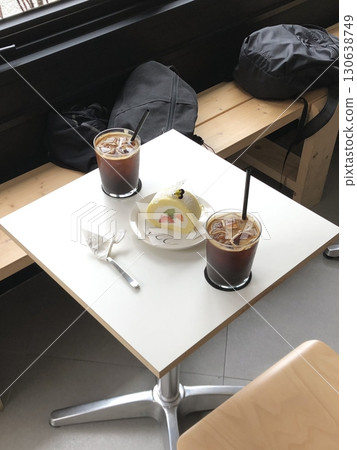 Refreshing ice americano and soft strawberry roll cake with creamy filling served on a cozy cafe table, offering a perfect mix of bold coffee and sweet indulgence in every peaceful bite and sip. 130638749