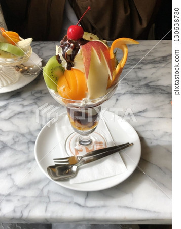Creamy pudding a la mode topped with fresh fruits and a scoop of ice cream, offering a perfect harmony of smooth, sweet, and refreshing flavors in every elegant and delightful spoonful. 130638780