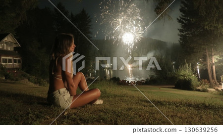 Young Woman Enjoying Retro Americana Vibes Amidst Nighttime Fireworks Display Young Woman Enjoying Retro Americana Vibes Amidst Nighttime Fireworks Display 130639256