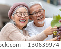 Happy senior couple smiling and enjoying grape harvesting together, holding a bunch of grapes in an outdoor setting, dressed warmly and sharing a joyful moment Happy senior couple smiling and enjoying grape harvesting together, holding a bunch of grapes in an outdoor setting, dressed warmly and sharing a joyful moment 130639974