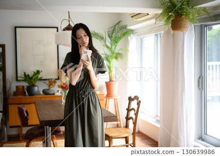 Smiling woman and smartphone in the dining room 130639986