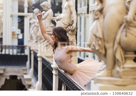 Ballet dancer posing gracefully near stone statues 130640632