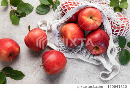 Fresh red apples spilling from reusable mesh bag on table Fresh red apples spilling from reusable mesh bag on table 130641810