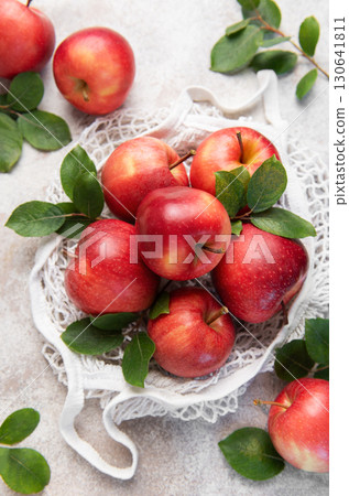 Fresh red apples with leaves in reusable shopping bag on table Fresh red apples with leaves in reusable shopping bag on table 130641811