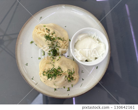 Traditional uzbek dumplings, manti with sour cream and herbs in asian restaurant 130642161