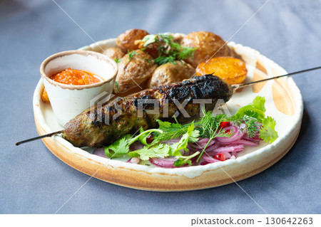 Georgian lula kebab plate. Bbq skewer, traditional barbecue dish with baked potatoes, sauce 130642263