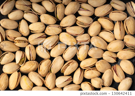 Fried salt pistachio nuts texture background. Baked pistachios pattern, roasted green pistache Fried salt pistachio nuts texture background. Baked pistachios pattern, roasted green pistache 130642411