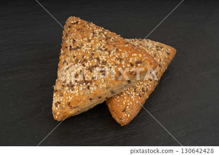 Triangular bun closeup. Wheat bread with sesame and flax seeds, healthy whole grain bakery 130642428