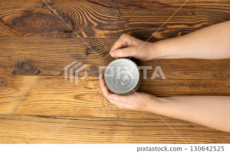 Hand Holds Cup, Empty Cup in Hands, Coffee Mug, Teacup Mockup, Cup in Arms on Wooden Table 130642525