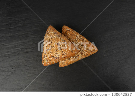 Triangular bun closeup. Wheat bread with sesame and flax seeds, healthy whole grain bakery 130642827