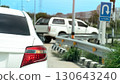 Rear side of white car with right turn signal. Open for u-turn on the road. Front of car the other car waiting for u-turn and sign board for u-turn. Background of city under blue sky. 130643240
