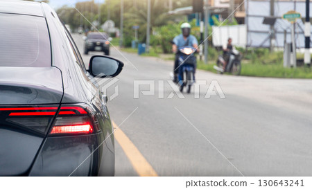 Rear side of grey car turn on brake light. Stop on asphalt road. Opposite of road with motorcycle with driving in city upcountry of Thailand. 130643241