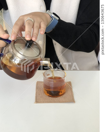A steaming cup of hot tea with a rich aroma and soothing warmth. Perfect for relaxation or a refreshing pick-me-up. Enjoy its comforting flavor plain or with a touch of honey. 130643675