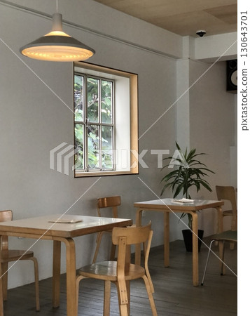 Cozy cafe interior with modern decor, comfortable seating, and warm lighting. A perfect spot for enjoying coffee or tea, creating a relaxed and inviting atmosphere for guests. 130643701