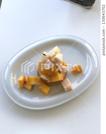 A delightful fruit tart with a buttery, flaky crust filled with creamy custard and topped with an array of fresh, vibrant fruits. Perfectly balanced between sweet and tangy, making it irresistible 130643702