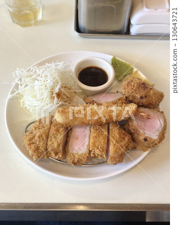 Crispy tonkatsu, a Japanese-style breaded and deep-fried pork cutlet, served with shredded cabbage and drizzled with savory sauce. A delightful balance of crunchy texture and juicy meat. 130643721