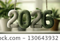 Soft knitted 2026 numbers suspended on string, cozy textile art with green plants for eco-friendly new year, celebration, and sustainable design backgrounds 130643932
