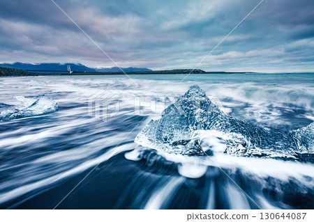 Ice fragments on black sand. Popular tourist attraction. Location Vatnajokull, Jokulsarlon lagoon, Iceland, Europe. 130644087