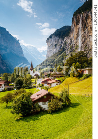 Great view of alpine village glowing by sunlight. Location Swiss alps, Lauterbrunnen valley, Staubbach waterfall, Europe. Great view of alpine village glowing by sunlight. Location Swiss alps, Lauterbrunnen valley, Staubbach waterfall, Europe. 130644341