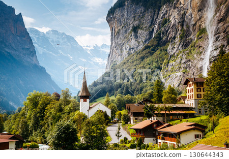 Great view of alpine village glowing by sunlight. Location Swiss alps, Lauterbrunnen valley, Staubbach waterfall, Europe. 130644343