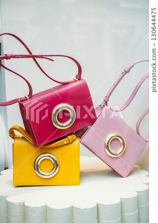 Colorful handbags with oversized metallic rings on display in a boutique window. Dopamine dressing accessories, playful fashion, statement design, mood-boosting style 130644475