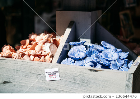 Assorted scented plaster ornaments in lavender and terracotta hues displayed in a rustic wooden box. Fragrance craft, artisanal home decor, sensory design, handmade objects 130644476