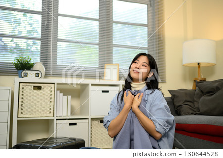 Traveler getting ready for a trip, smiling while packing belongings in a living room Traveler getting ready for a trip, smiling while packing belongings in a living room 130644528