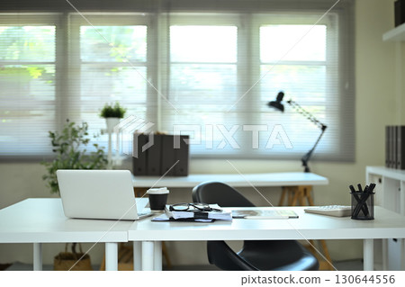 Modern office desk with laptop, coffee cup, and documents in bright workspace 130644556