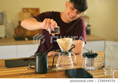 Happy caucasian man preparing fresh pour over coffee in a cozy kitchen 130644559