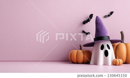 Halloween ghost decoration with purple hat and pumpkins on pink background, creating a festive and playful autumn atmosphere for celebrations 130645150