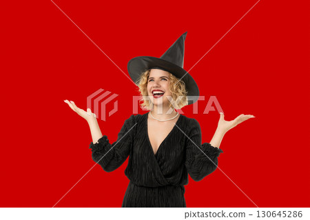 Witch smiles and gestures joyfully while dressed for Halloween 130645286