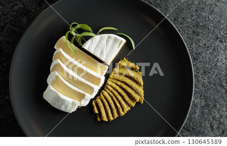 Camembert cream cheese with pesto on a black plate. 130645389