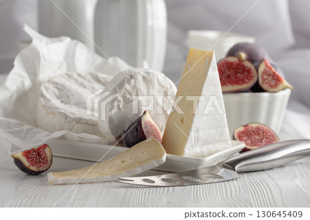 Camembert cheese with figs on a white table. 130645409