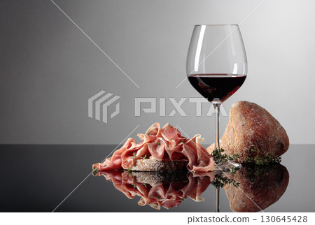 Prosciutto with ciabatta, red wine and thyme on a black background. Prosciutto with ciabatta, red wine and thyme on a black background. 130645428