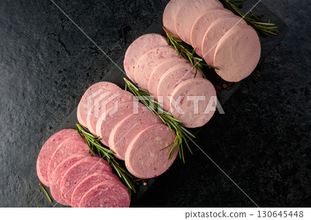 Various boiled sausages with rosemary on a black table. 130645448
